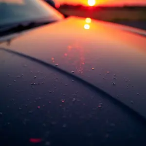 Capô de carro brilhante após aplicação de cera, refletindo o pôr do sol.