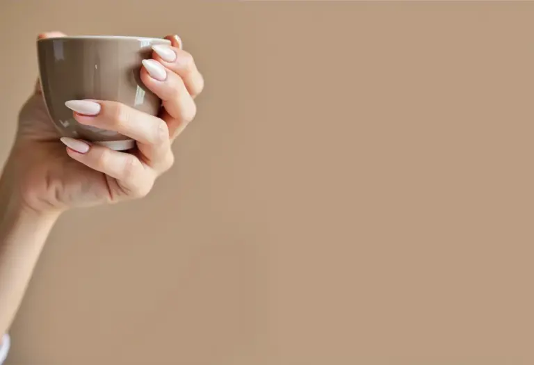 Unhas amendoadas cor nude segurando xícara de chá