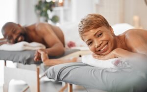Um casal recebendo massagem em um spa, sorrindo e relaxando